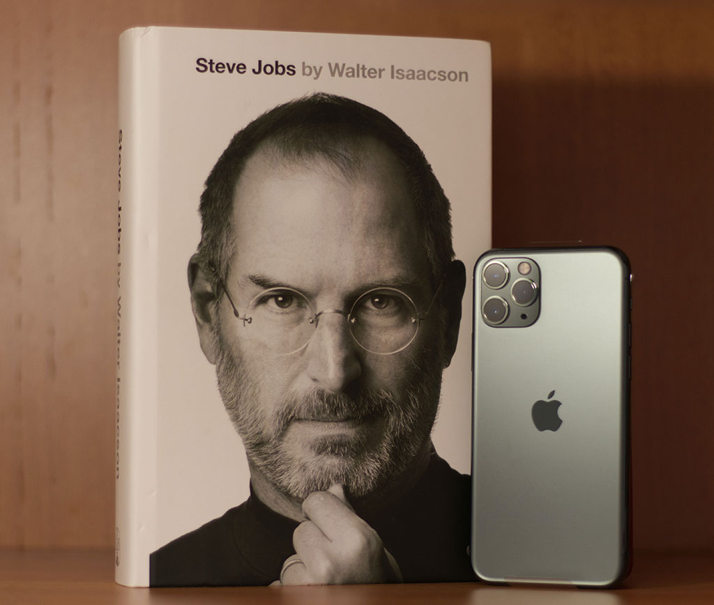 Steve Jobs Book and silver iPhone atop a table