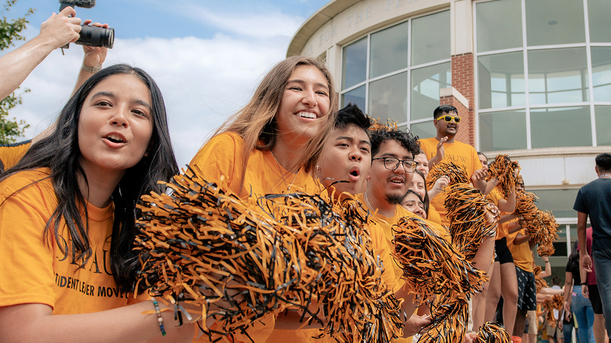 Students with pom-poms cheering on the incoming class on opening day